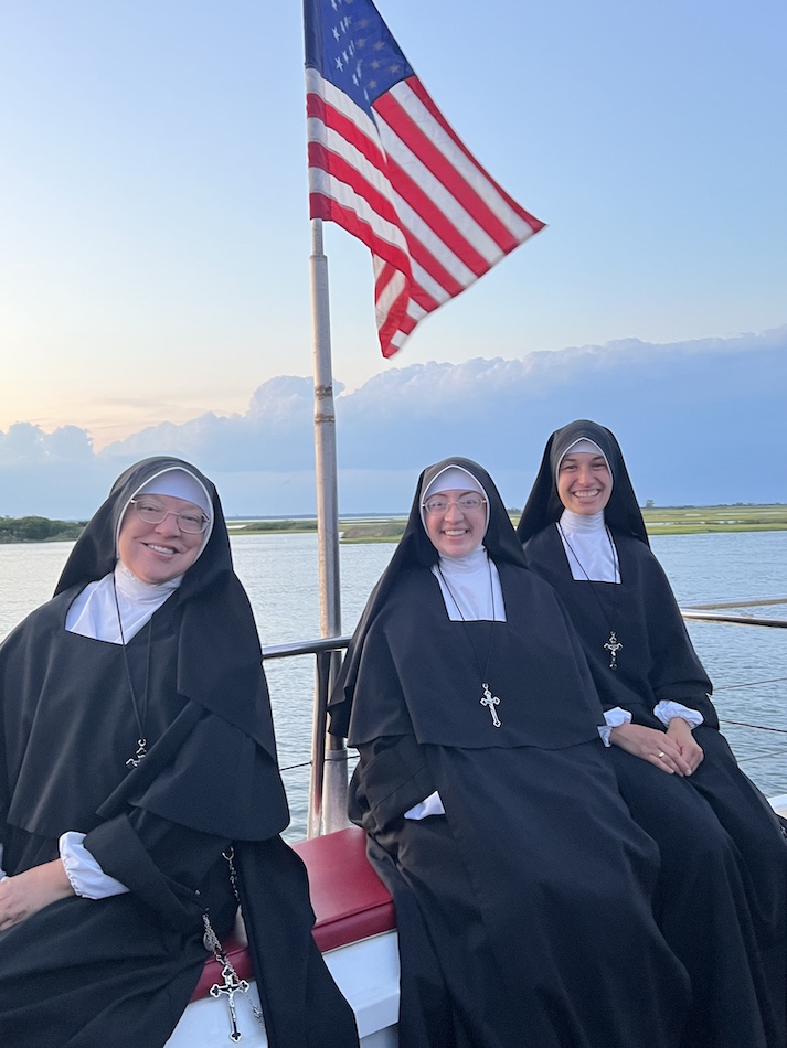 Three Sisters aboard a boat beneath the American flag