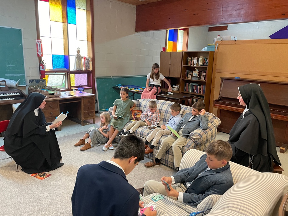A Sister reading aloud to students gathered around her